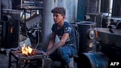 FILE - A young man sells heaters in the city of Raqqa, Nov. 11, 2022, amid a fuel crisis, as winter approaches in war-torn Syria.