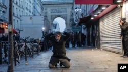 A member of Kurdish community kneels on the ground as he is detained during clashes stands with police officers near the crime scene where a shooting took place in Paris, Dec. 23, 2022.