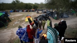 FILE - Asylum-seeking migrants gather around a fire to warm up during a day of high winds and low temperatures at a makeshift encampment near the border between the U.S. and Mexico, in Matamoros, Mexico, Dec. 23, 2022.