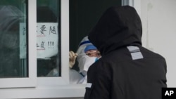 A worker in protective gear prepares a COVID-19 test inside a hospital compound in Beijing, China, Dec. 15, 2022. 