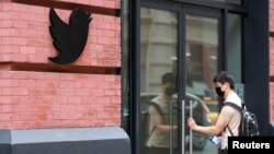 FILE - A person wearing a mask prepares to enter Twitter offices in Manhattan, New York City, July 29, 2021.