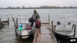 ARHIVA - Čovek napušta svoj dom i odlazi u letnju vikendicu na ostrvu na reci Dnjepar posle napada na skladište nafte u Hersonu 20. novembra 2022. godine, usred ruske invazije na Ukrajinu.