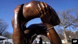 Un transeúnte camina bajo la escultura de bronce de 20 pies de altura "El Abrazo", un monumento al Dr. Martin Luther King Jr. y Coretta Scott King, en el Boston Common, el 10 de enero de 2023, en Boston, EEUU,