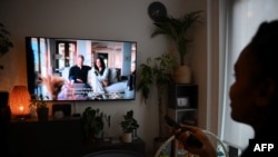 A woman poses watches an episode of the newly released Netflix docuseries "Harry and Meghan" about Britain's Prince Harry, Duke of Sussex, and Britain's Meghan, Duchess of Sussex, in London, Dec. 8, 2022.