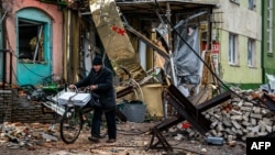 A local resident pushes his bicycle past "hedgehog" tank traps and rubble, down a street in Bakhmut, Donetsk region, Jan. 6, 2023, amid the Russian invasion of Ukraine.