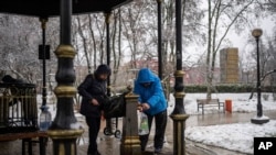 People collect water, in Kyiv, Nov. 24, 2022. Residents of Ukraine's bombed but undaunted capital clutched empty bottles in search of water and crowded into cafés for power and warmth Thursday.