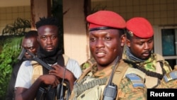 FILE - Burkina Faso's military leader Ibrahim Traore is escorted by soldiers in Ouagadougou, Oct. 2, 2022. He has faced several alleged coup attempts from within the military since he took power more than two years ago.