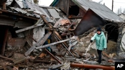 A woman stands near debris of her house following Russian shelling, in Kurakhove, Donetsk region, Ukraine, Dec. 8, 2022.