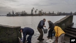 Los residentes de la ciudad recientemente liberada de Jersón recogen agua de la orilla del río Dnipro, cerca de la línea del frente, en el sur de Ucrania, el lunes 21 de noviembre de 2022. (Foto AP/Bernat Armangue)