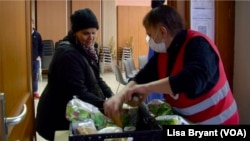 Zohra, left, who did not give her last name, packs up free food from the Salvation Army in Paris into her cart. Like many Europeans, she is having a hard time making ends meet. 
