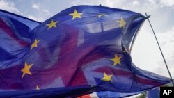 FILE - A European Union supporter flies the British flag behind a European Union flag, outside the Houses of Parliament, in London, Oct. 19, 2022. 