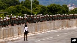 A woman walks in front of military police prepared for an announced protest by supporters of former President Jair Bolsonaro, in Brasilia, Brazil, Jan. 11, 2023. The protests did not take place.