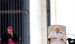 FILE - Pope Benedict XVI's personal secretary George Gaenswein, left, wipes his eye as the Pope delivers his message during his last general audience in St. Peter's Square at the Vatican, Feb. 27, 2013.