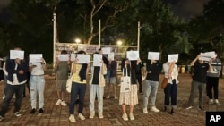 Protesters in Hong Kong hold up blank white papers on Nov. 28, 2022, during a commemoration for victims of a recent deadly fire in Urumqi, China. Students in Hong Kong chanted “oppose dictatorship” in a protest against China’s anti-virus controls.