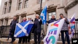 Para pengunjuk rasa membawa bendera Skotlandia di luar gedung Mahkamah Agung di London, Rabu, 23 November 2022.(AP Photo/Alberto Pezzali)