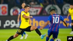 FILE - Huang Kaizho of Guangzhou Evergrande, left, fights for the ball against Leandro Velazquez of Johor Darul Ta'zim during a soccer match at Sultan Ibrahim Stadium in Johor, Malaysia, on April 15, 2022.