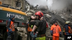 An emergency worker carries a wounded woman after a Russian missile destroyed a residential building in Dnipro, eastern Ukraine, Jan. 15, 2023.