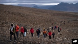 FILE - People climb to the top of what once was the Okjokull glacier, in Iceland, Aug. 18, 2019. With poetry, moments of silence and speeches about fighting climate change, officials, activists and others bid goodbye to the first Icelandic glacier to disappear.