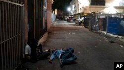 FILE - Two addicts sleep in an alley in Los Angeles, Sept. 21, 2022. 
