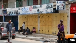 FILE - People sit in front of closed shops in the central business area of Accra, after shop owners in Ghana's capital closed their shops in protest of high costs, on Oct. 20, 2022.