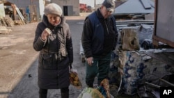 FILE - A woman cries and crosses herself after identifying the body of a missing neighbor, killed on the grounds of an industrial facility used by Russian forces in Bucha, Ukraine, April 4, 2022.