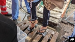 Plastic slippers are given to a man disembarking from the Geo Barents rescue ship carrying migrants in the Mediterranean Sea, at Salerno harbor, Italy, Dec. 11, 2022.