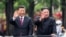 FILE - In this photo released by China's Xinhua News Agency, visiting Chinese President Xi Jinping, left, and North Korean leader Kim Jong Un wave from an open top limousine as they travel along a street in Pyongyang, North Korea, on June 20, 2019. 
