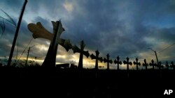 FILE - A truck passes crosses placed along the highway to honor the victims killed in the recent school shooting at Robb Elementary School, in Uvalde, Texas, June 6, 2022.