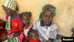 FILE - A woman who fled the violent rebellion in Central African Republic (CAR) sits with her family as they wait for their identification process in the border town of Garoua Boulai, Cameroon, Jan. 7, 2021.