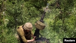 A Ukrainian service member shoots from an automatic grenade launcher at a position on the front line, amid Russia's attack on Ukraine, near Bakhmut, Donbas region, Ukraine, June 5, 2022. 