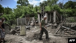 A man walks through the yard of a damaged house after shelling in which two people were killed in the city of Lysychansk in the eastern Ukrainian region of Donbas, June 13, 2022.