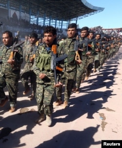 FILE - Troops of the Syrian Democratic Forces celebrate the first anniversary of the liberation of Raqqa province from the Islamic State group, in Raqqa, Syria, Oct. 27, 2018.