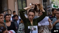 Nasibe Samsaei, an Iranian woman living in Turkey, cuts her ponytail off during a protest outside the Iranian Consulate in Istanbul, Sept. 21, 2022, following the death of an Iranian woman after her arrest by the country's morality police in Tehran.