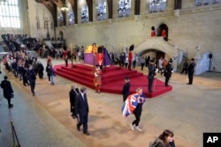 People pay their respects as they walk past the coffin of Britain's Queen Elizabeth, draped in the Royal Standard with the Imperial State Crown and the Sovereign's orb and scepter, inside Westminster Hall in London, Sept. 16, 2022.
