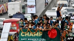 নেপালে সাফ নারী শিরোপা জয়ী বাংলাদেশের নারী ফুটবল দলের সদস্যরা,ঢাকায় খোলা ছাদের বাসে দাঁড়িয়ে সমর্থকদের দিকে হাত নাড়ছেন। (ছবি মুনির উজ জামান / AFP)