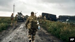 Tentara Ukraina berdiri di jalan di wilayah yang baru saja mereka rebut kembali di wilayah Kharkiv, Ukraina, Senin 12 September 2022.