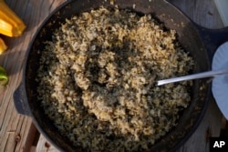 A fresh pot of hand-harvested and processed wild rice is shared by students and faculty of Leech Lake Tribal College as a part of a traditional Ojibwe ceremony, Sept. 12, 2022, in Cass Lake, Minnesota.