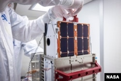 DART team engineers lift and inspect the LICIACube CubeSat after it arrived at the Johns Hopkins Applied Physics Laboratory (APL) in Laurel, Maryland in August. The miniaturized satellite will deploy 10 days before DART's asteroid strike. (Image Credits: NASA/Johns Hopkins APL/Ed Whitman)