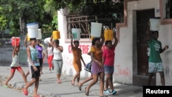 Adolescentes acarrean agua en bidones de plástico en medio de la estrechez económica y el auge del crimen organizado, en Puerto Príncipe, Haití el 17 de septiembre de 2022.