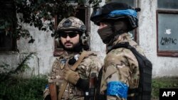 Ukrainian police officers from a special unit take shelter from rain in the frontline town of Kupiansk, Kharkiv region, Sept. 24, 2022, amid Russia's continuing invasion of Ukraine.