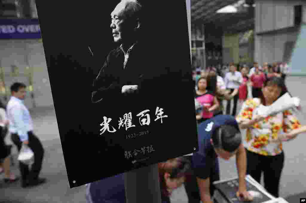 Office workers in the financial district buy special edition local newspapers which feature the life of the late Lee Kuan Yew, Singapore, March 23, 2015.