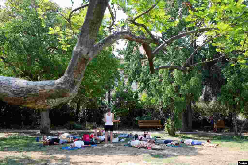 Un grupo de personas aprovecha las sombras de los árboles para practicar yoga en Niza Francia, el 18 de julio de 2022.