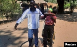 Jason, who had been separated from his family during a long-standing conflict in south-eastern Congo, is hugged by his grandmother while his uncle reacts after the International Committee of the Red Cross (ICRC) reunited them in Manono, Democratic Republi