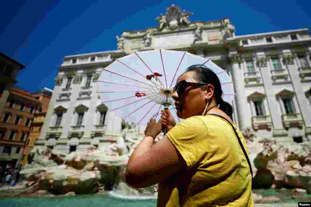 Una mujer se protege del sol bajo una sombrilla en la Fontana di Trevi en Roma,&nbsp; el 19 de julio de 2022.