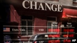 Exchange rates for U.S dollars and the euro currencies are displayed outside a change office, July 13, 2022 in Paris. The euro this month fell to parity with the dollar for the first time in nearly 20 years.