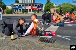 Ernst Hoermann, 72, has his hand removed from the ground after he glued it during a protest as part of the Uprising of the Last Generation in Berlin on Monday, July 11, 2022.
