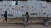 Un chauffeur de moto-taxi attend des clients devant un mur recouvert d'affiches de campagne à Kisumu, dans l'ouest du Kenya, le 16 juillet 2022.