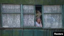 A local resident stands in the window as she looks at a school building damaged by a Russian military strike, amid Russia's invasion on Ukraine, in the town of Kostiantynivka, Ukraine, July 13, 2022. 