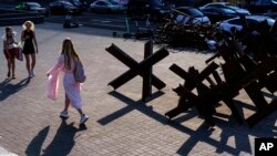 Barricades to prevent Russian troops from invading the city sit along a street as pedestrians walk by in Kyiv, Ukraine, July 28, 2022. 
