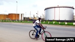 ARCHIVES - Un homme fait du vélo près des installations de la Société ivoirienne de raffinage, le 16 novembre 2016, à Abidjan.